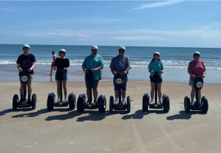 people on electric scooters on the beach at fun coast tours